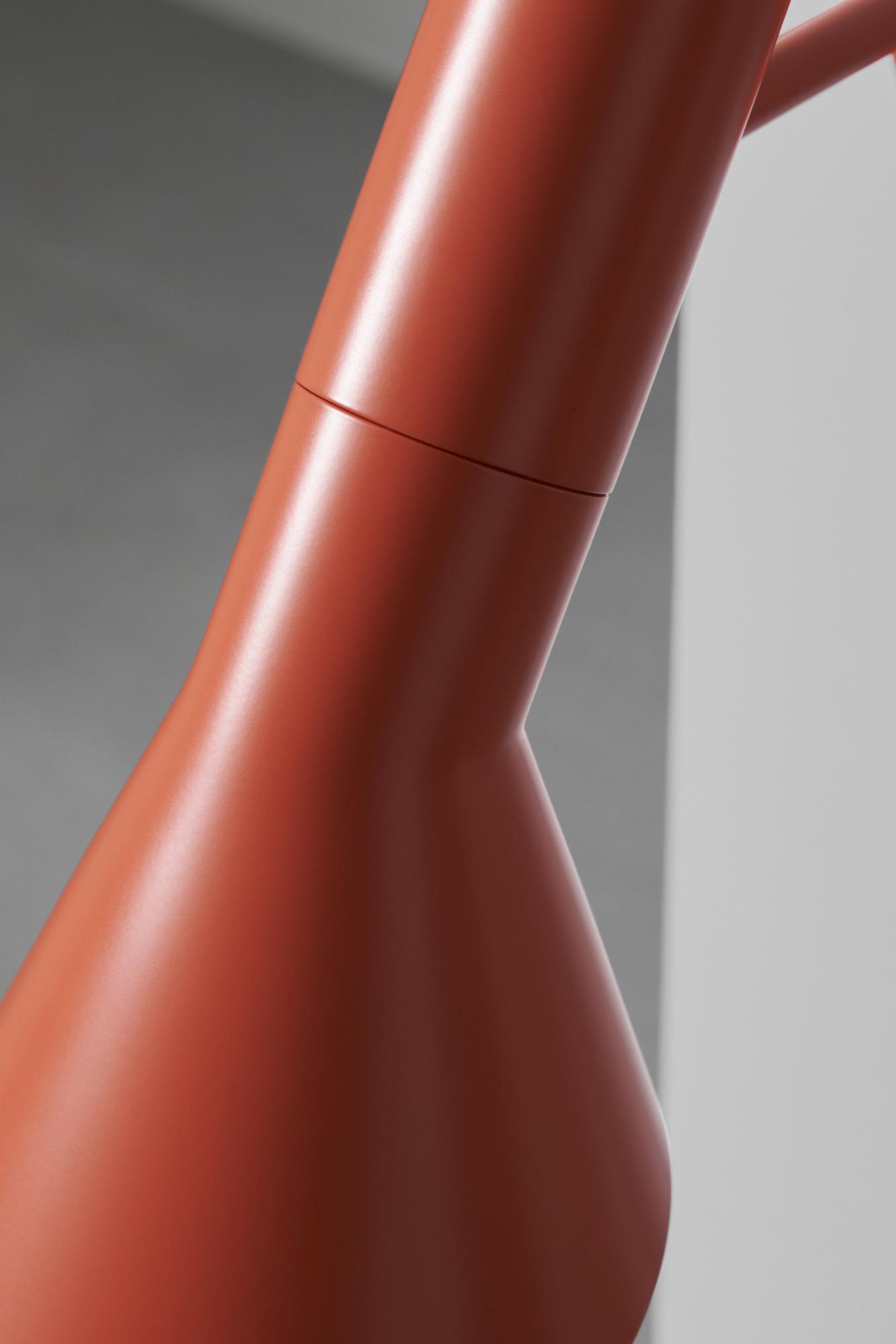 AJ Wall lamp in electric orange with a sleek design against a dark podium, © 2025 Louis Poulsen.