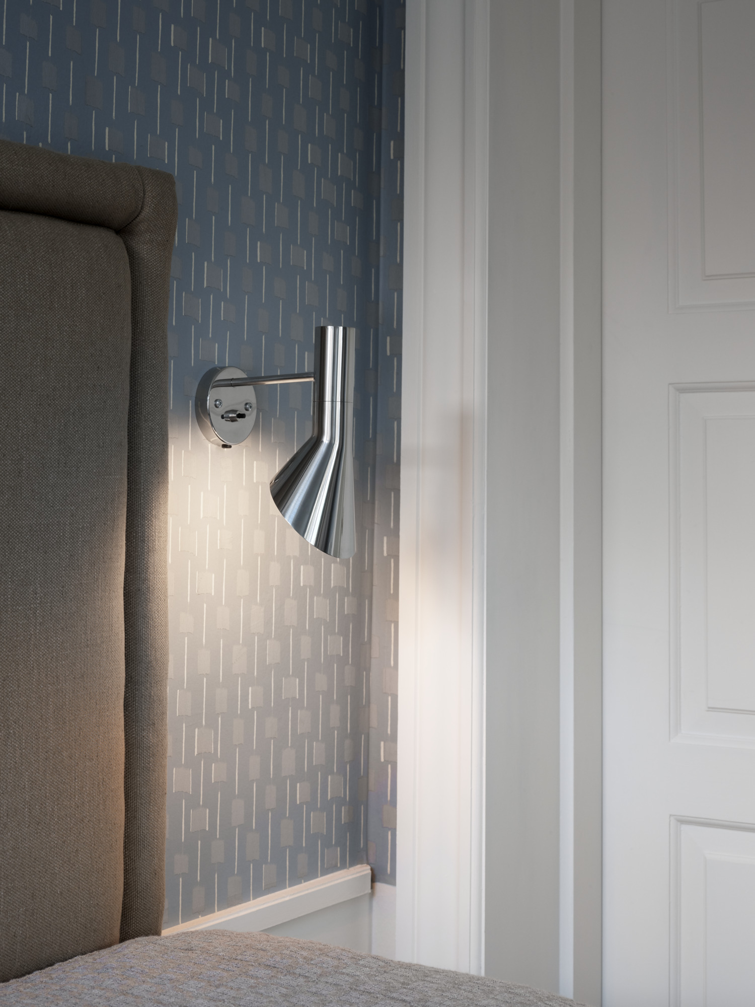 AJ Wall lamp in stainless steel on a decorative wall in a modern space, © 2025 Louis Poulsen.