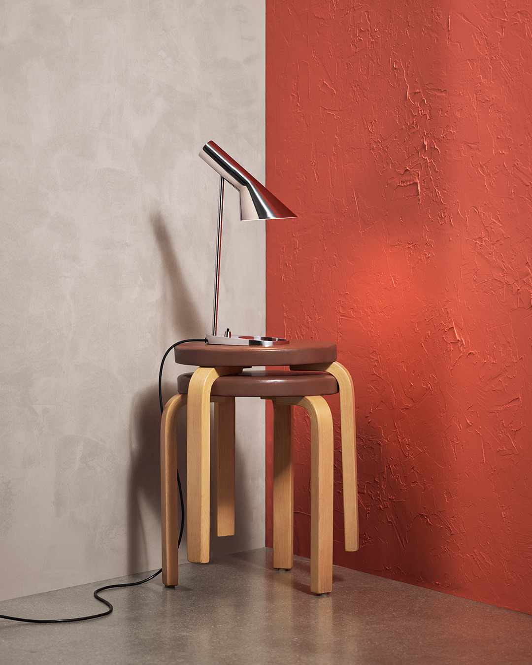  AJ Mini Table lamp in stainless steel on a wooden table, featuring classic design, © 2025 Louis Poulsen.