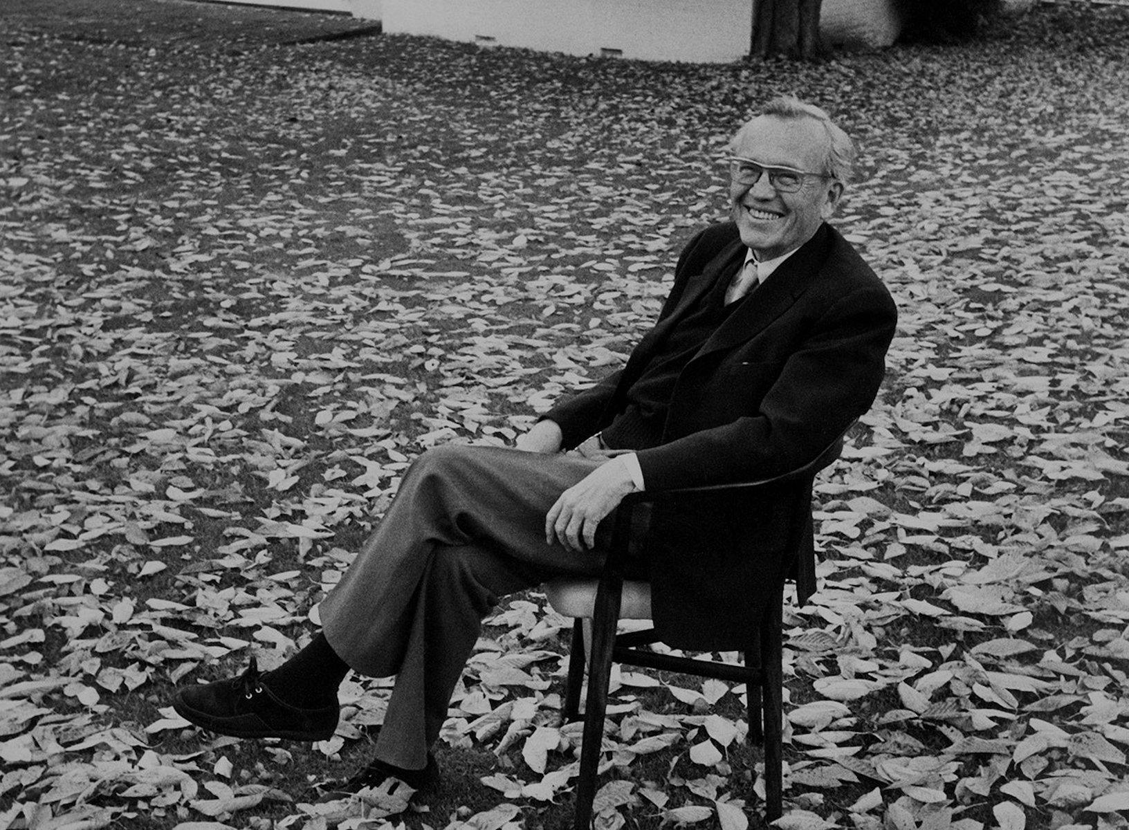 Finn Juhl smiling while seated outdoors, © 2025 Louis Poulsen.