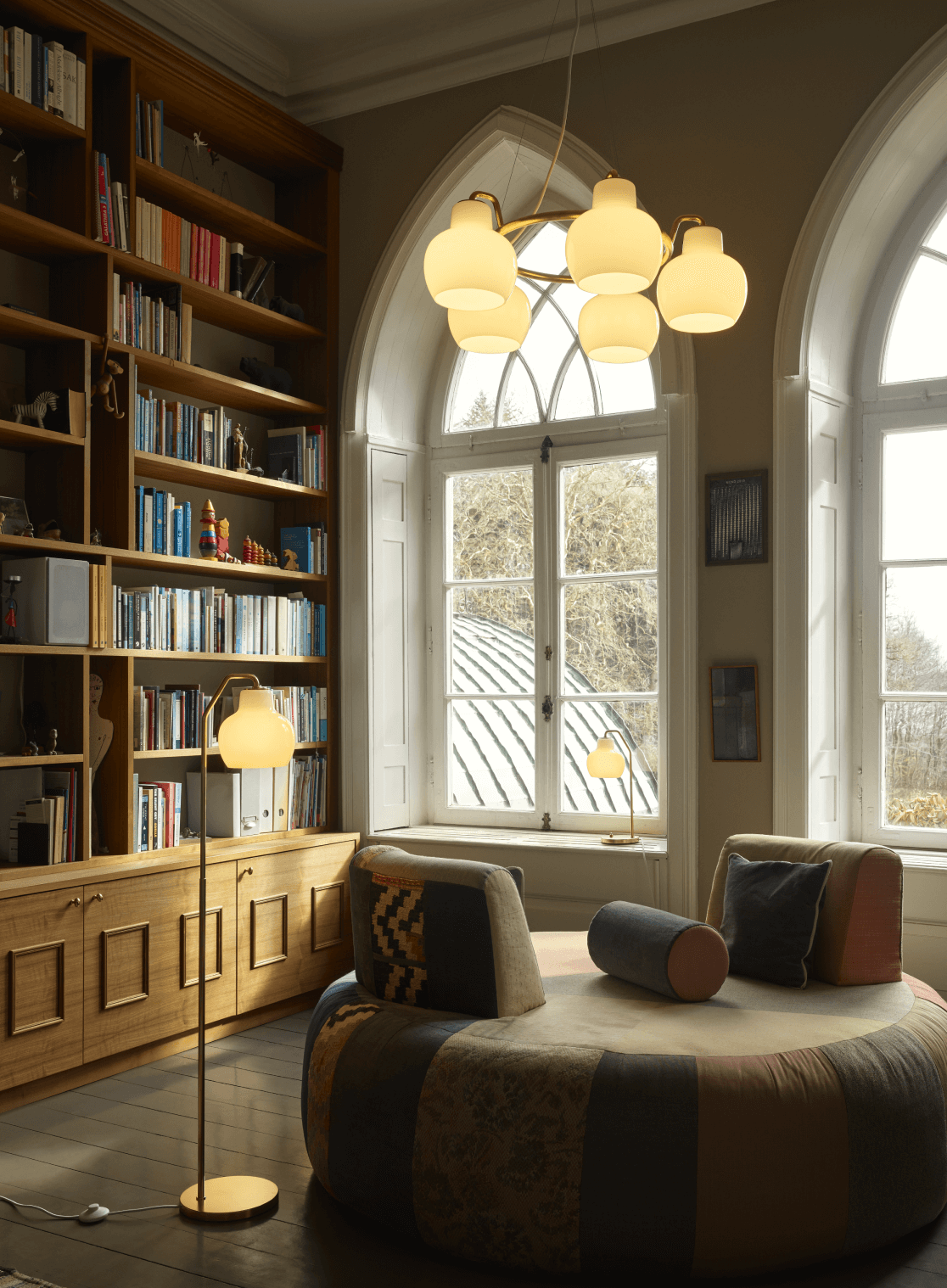 VL Ring Crown pendant and floor lamps in cozy library with arched windows, © 2025 Louis Poulsen.