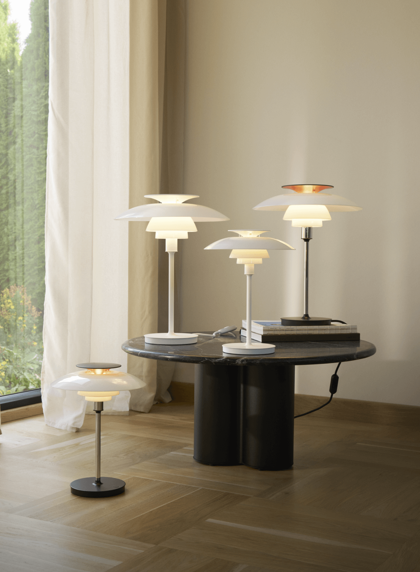 PH 80 table lamps on a marble table with books and soft lighting, © 2025 Louis Poulsen.
